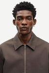Man wearing a brown jacket by Samsoe Samsoe with a zipper on a white background