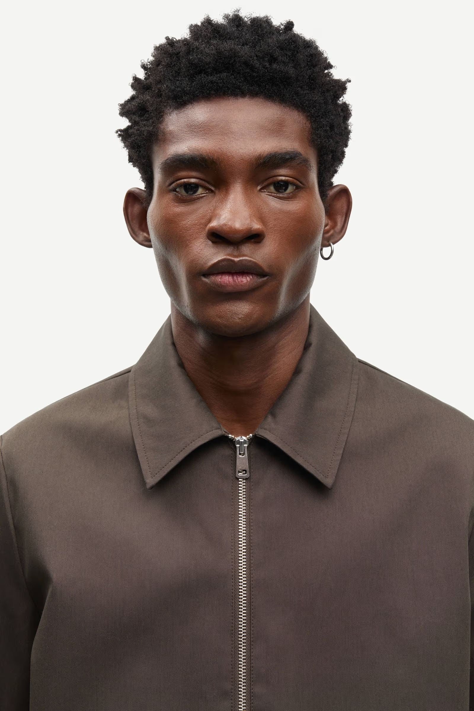 Man wearing a brown jacket by Samsoe Samsoe with a zipper on a white background