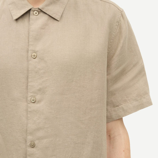Beige short-sleeve shirt by Samsoe Samsoe worn by a person on a white background close up