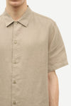 Beige short-sleeve shirt by Samsoe Samsoe worn by a person on a white background close up