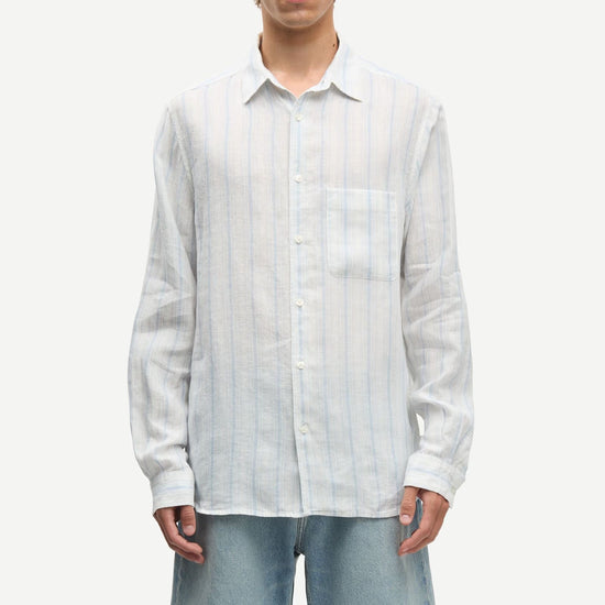 Man wearing a blue and white striped shirt by Samsoe Samsoe and denim shorts on a white background