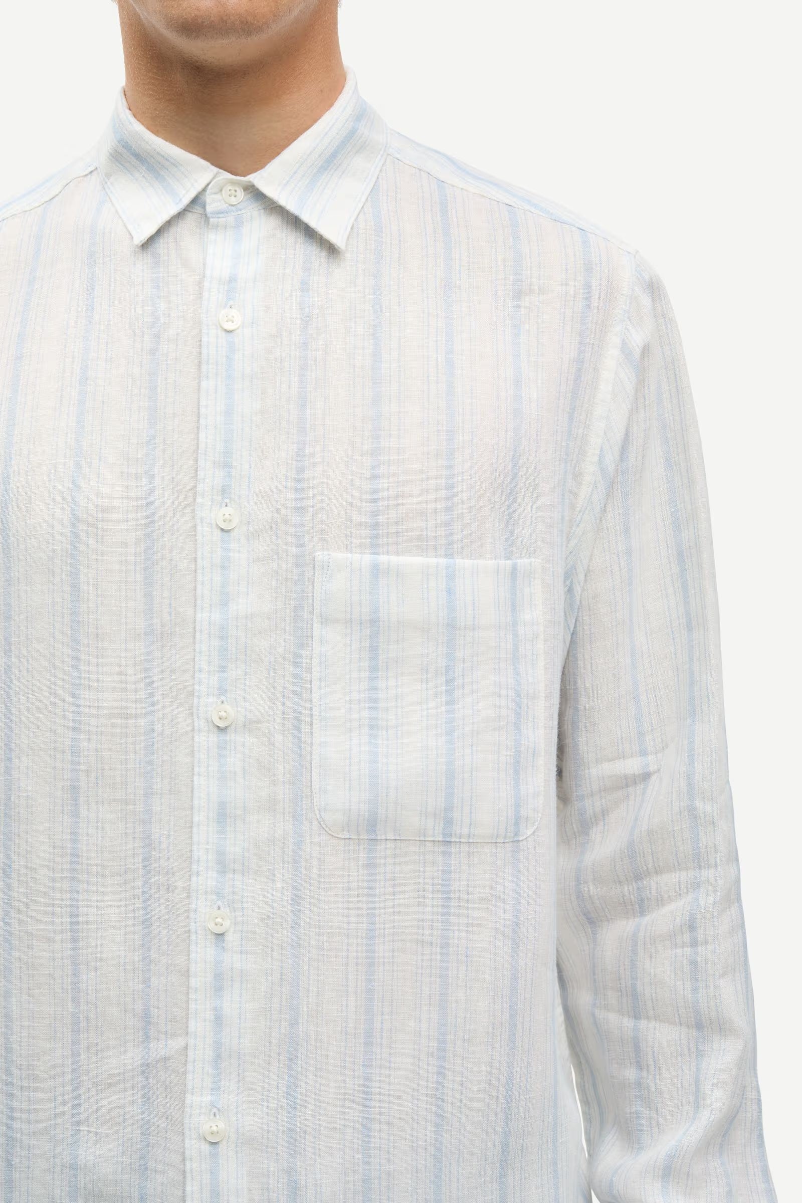 Light blue and white striped shirt by Samsoe Samsoe worn by a person on a white background close up