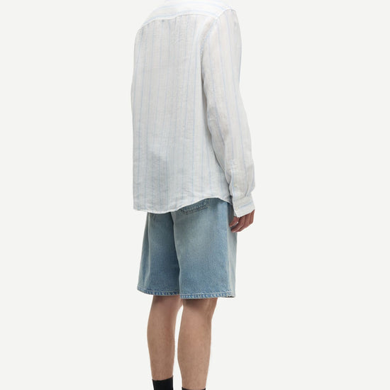 Man wearing a blue and white striped shirt by Samsoe Samsoe and denim shorts on a white background rear view