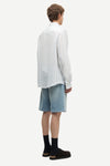 Man wearing a blue and white striped shirt by Samsoe Samsoe and denim shorts on a white background rear view