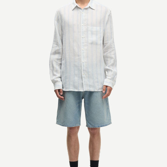 Man wearing a blue and white striped shirt by Samsoe Samsoe and denim shorts on a white background full outfit