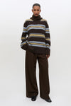 Woman wearing striped brown yellow and pale blue knit with brown trousers
