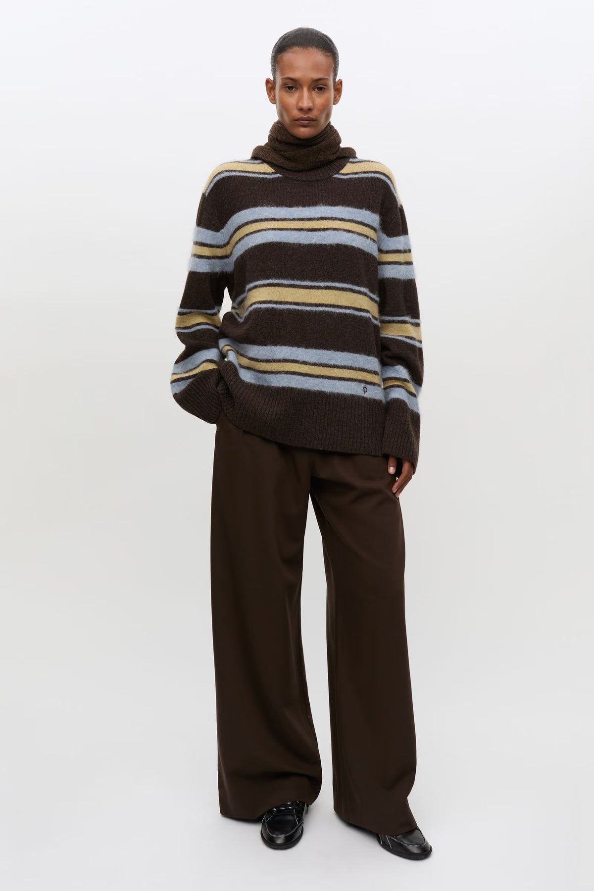 Woman wearing striped brown yellow and pale blue knit with brown trousers