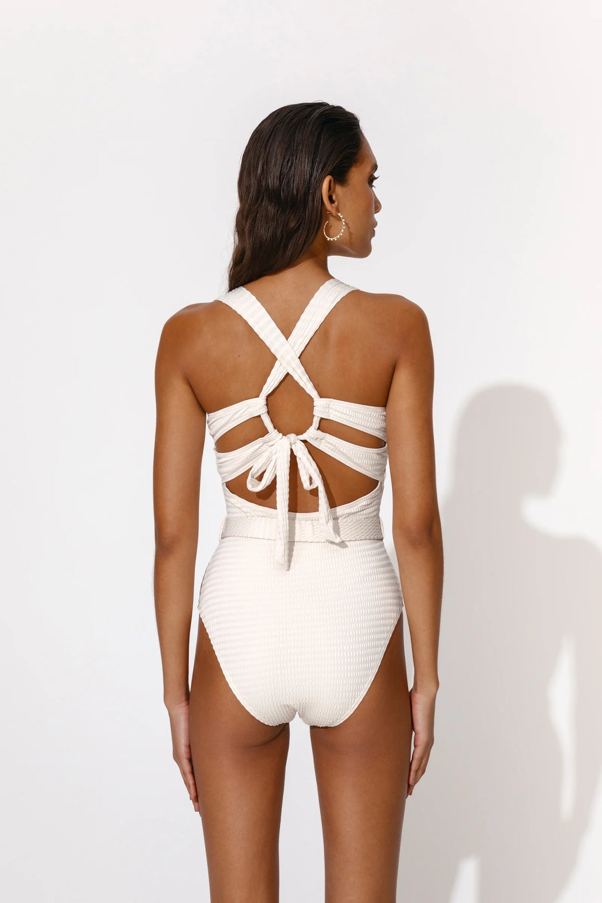 Off white swimsuit with moulded cups thick straps and attached belt with circular tortoise shell look buckle with tie strap details at the back