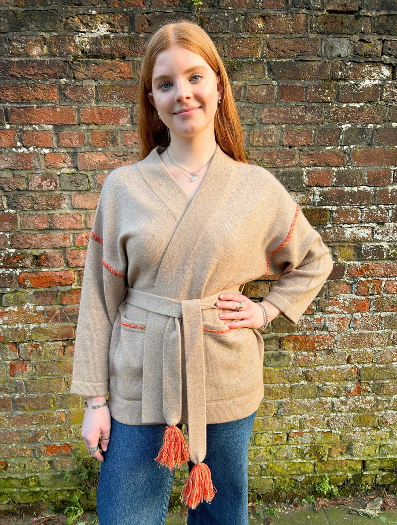 Beige wrap belted cardigan with contrast orange and yellow stitching at top of arms and pockets with a palm tree sewn onto the back