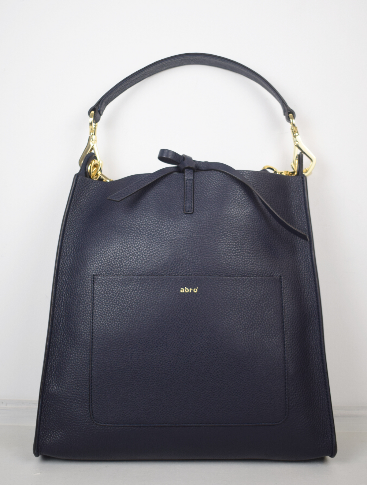 navy leather bag with cross body strap and small handle.
