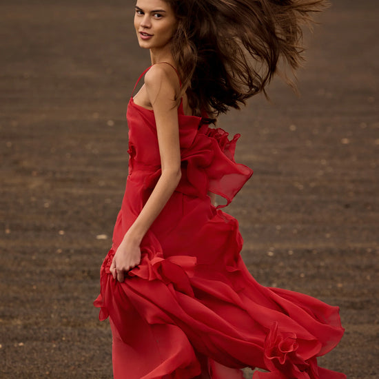 Woman in a red dress with flowing hair on a dark, textured surface