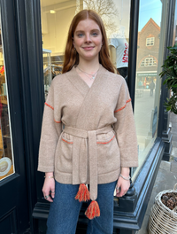 Beige wrap belted cardigan with contrast orange and yellow stitching at top of arms and pockets with a palm tree sewn onto the back