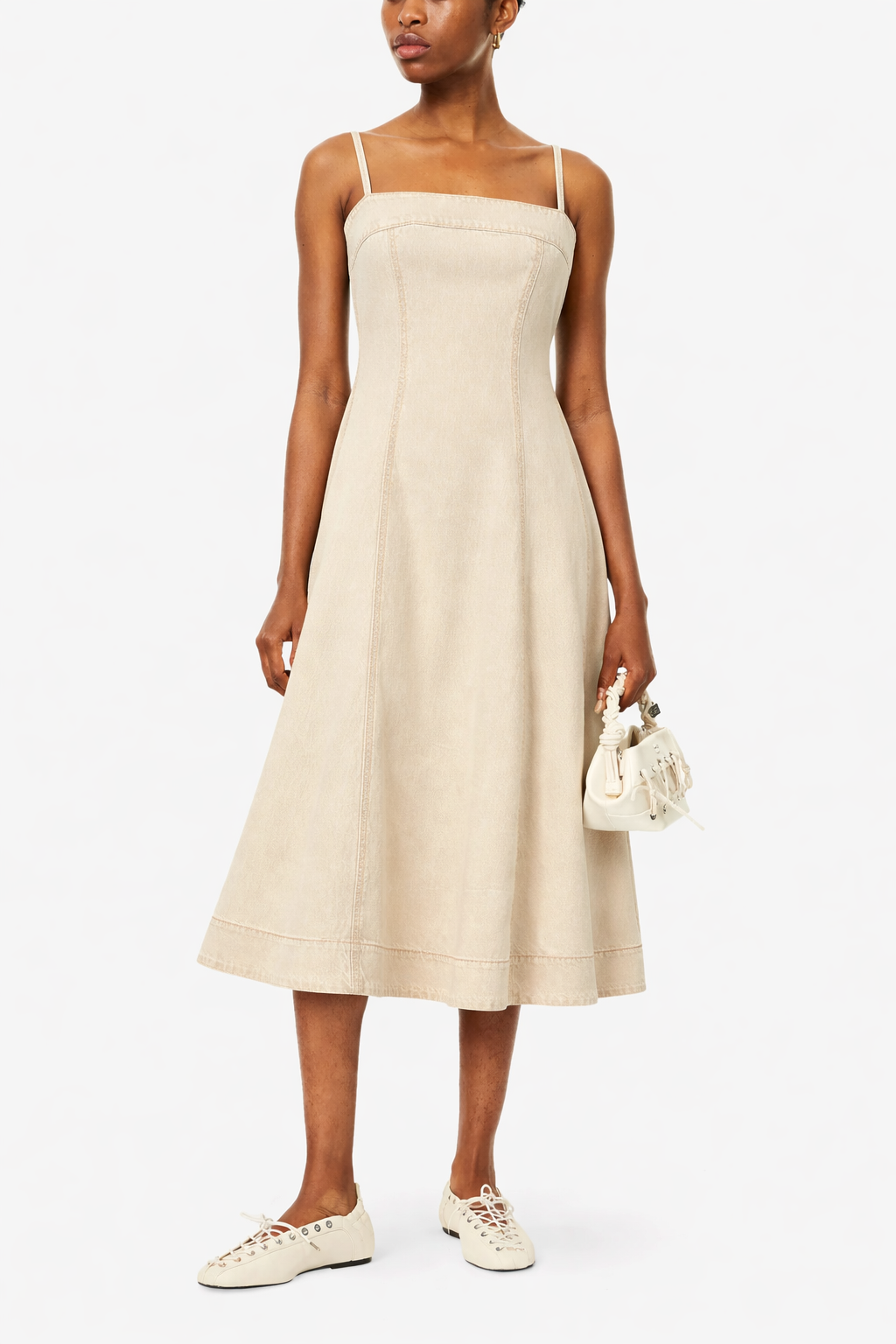 Woman wearing a ecru dress with white sneakers on a white background from Paige