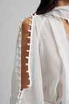 white long sleeved shirt with bow neck and covered buttons down the raglan sleeves
