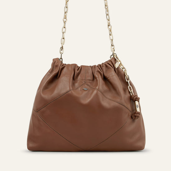 Brown leather handbag with chain handle on a beige background from bash