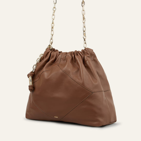 Brown leather handbag with a drawstring top on a white background from bash