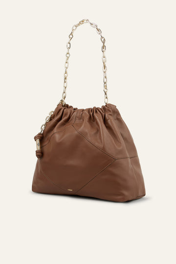 Brown leather handbag with a drawstring top on a white background from bash
