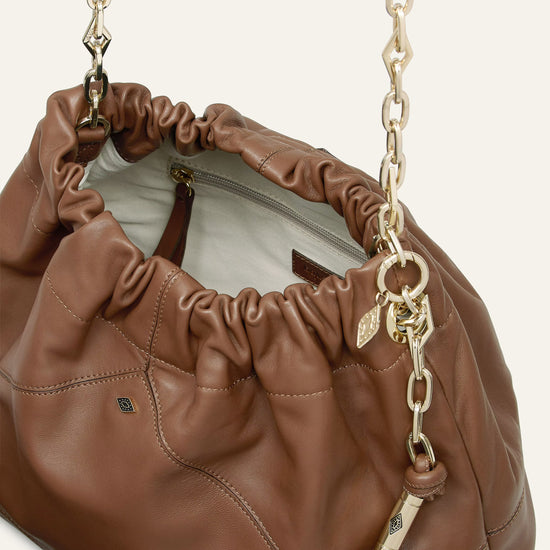 Brown leather handbag with gold chain strap on a white background from bash