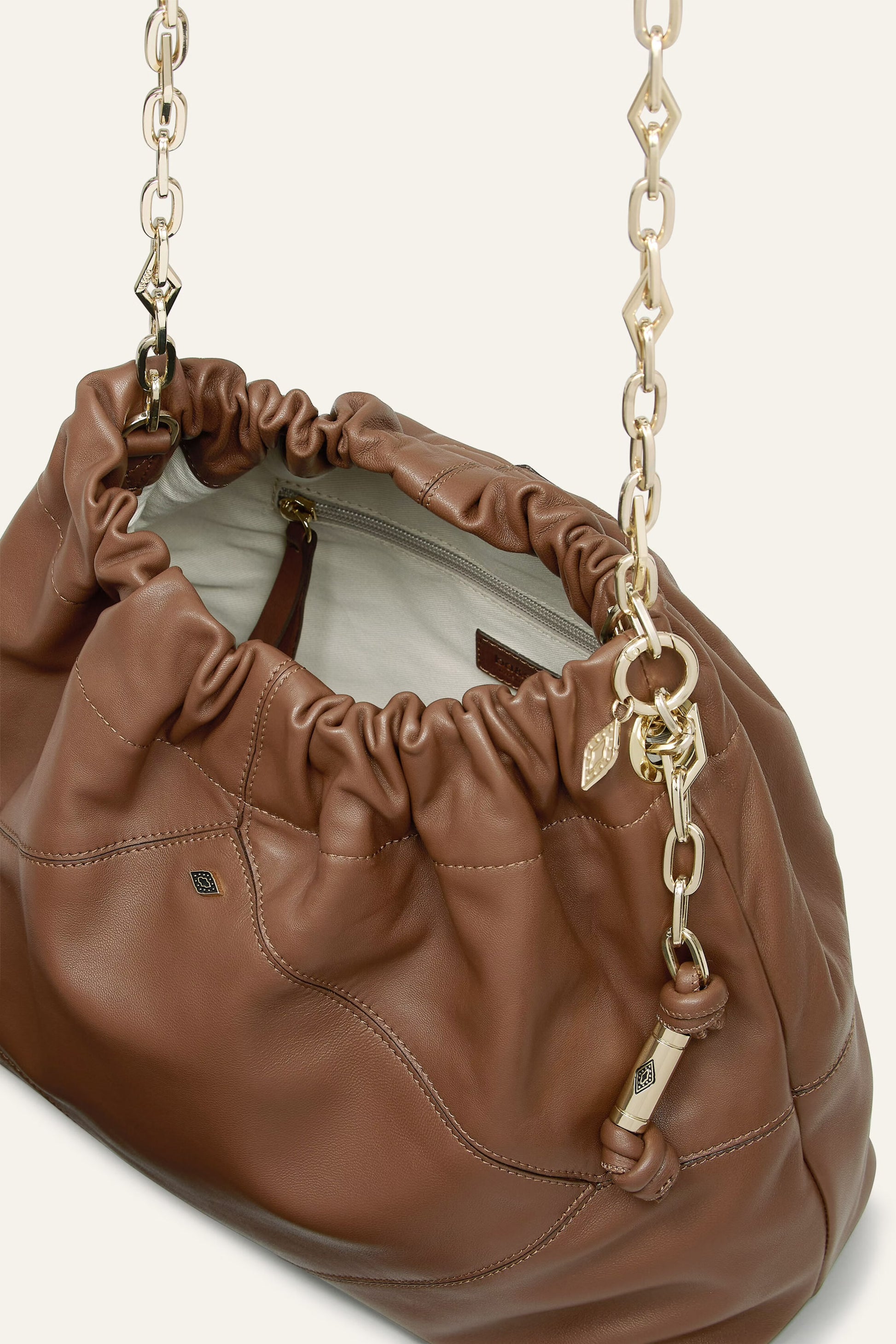 Brown leather handbag with gold chain strap on a white background from bash