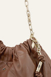 Brown leather handbag with gold chain and decorative clasp on a beige background from bash