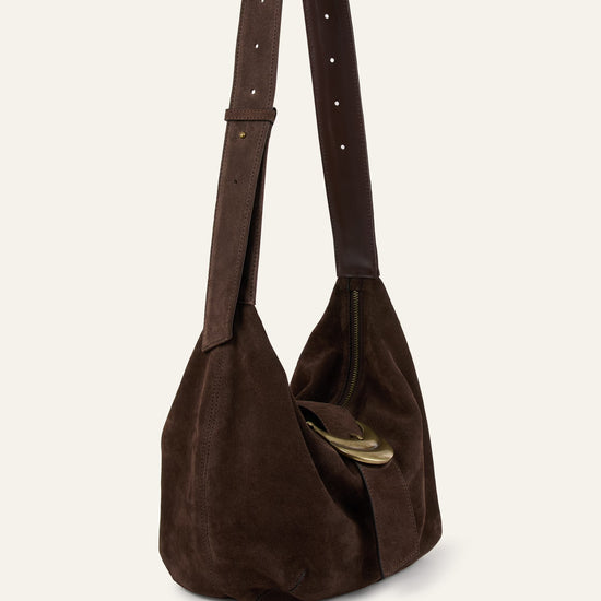 Brown suede handbag with a strap on a beige background