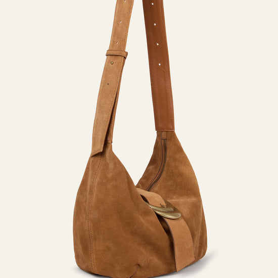 Brown suede handbag with a strap on a beige background