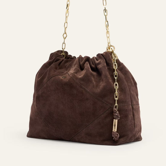 Brown suede handbag with gold chain handle on a white background