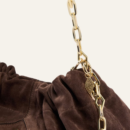 Brown bag with a gold chain detail on a beige background