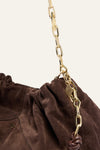 Brown bag with a gold chain detail on a beige background