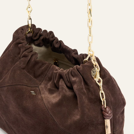 Brown suede handbag with a gold chain strap on a white background