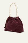 A burgundy suede bucket bag with a gold chain shoulder strap, shown on a light cream background.