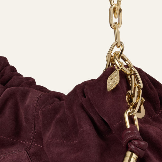 Burgundy suede bag on white background close up of chain