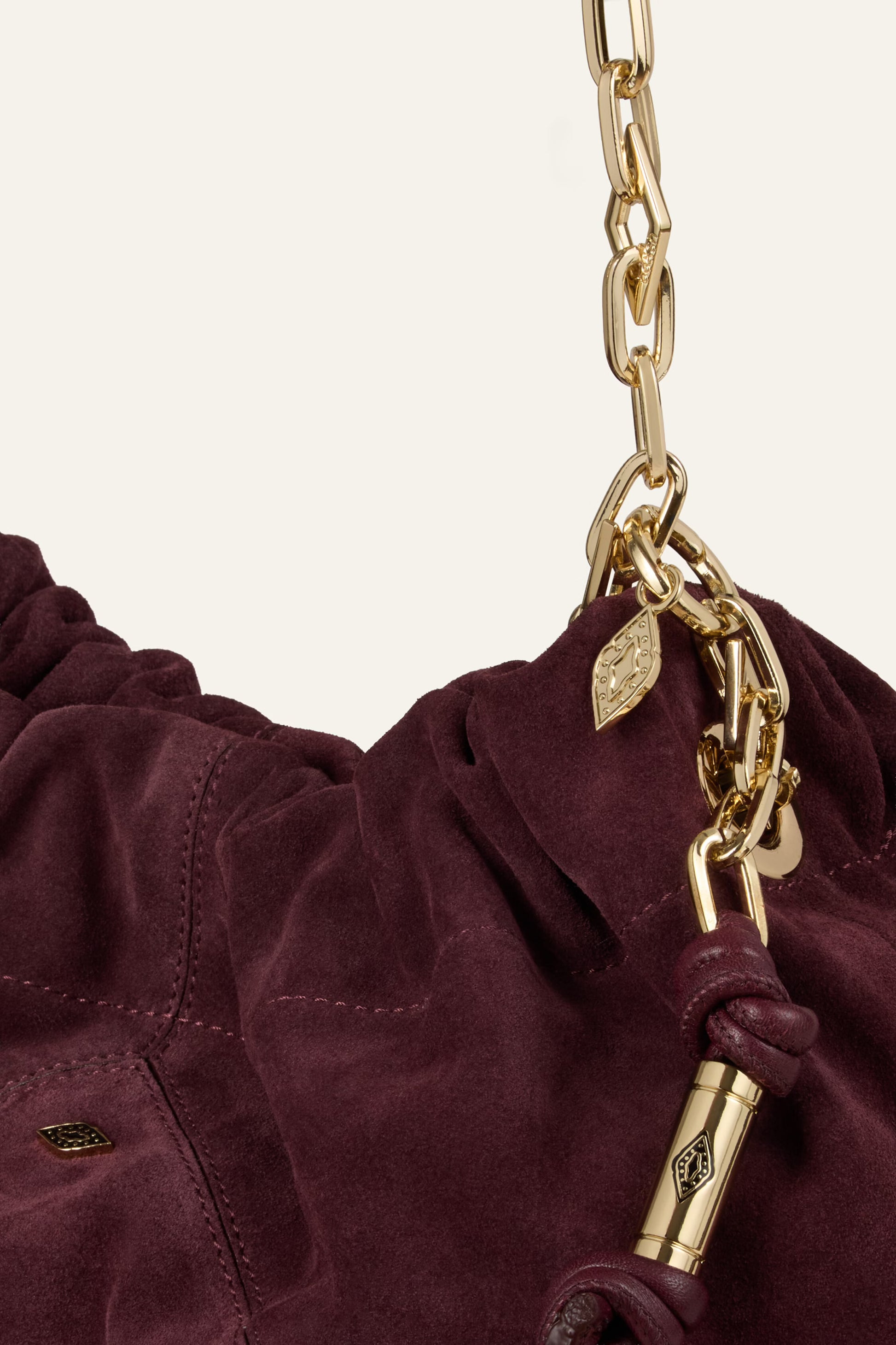 Burgundy suede bag on white background close up of chain