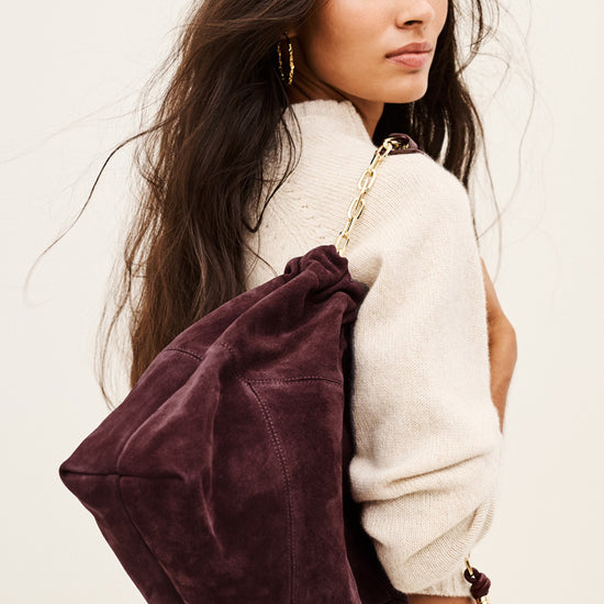 woman wearing Burgundy suede bag on white background