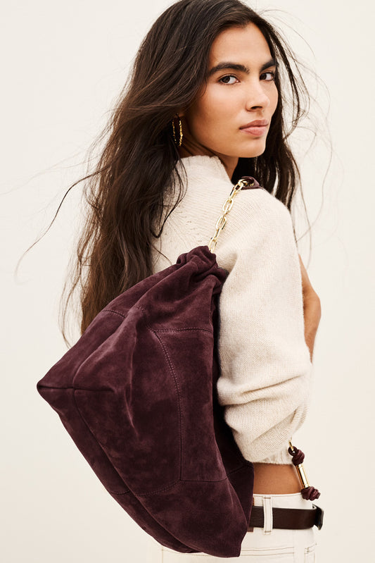 woman wearing Burgundy suede bag on white background