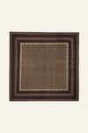 A square brown woven textile with a geometric border pattern, displayed flat against a light cream background.