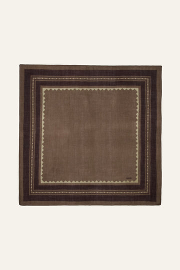 A square brown woven textile with a geometric border pattern, displayed flat against a light cream background.
