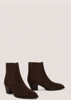 A pair of dark brown suede ankle boots with ribbed elastic side panels and low block heels, displayed against a solid light beige background.