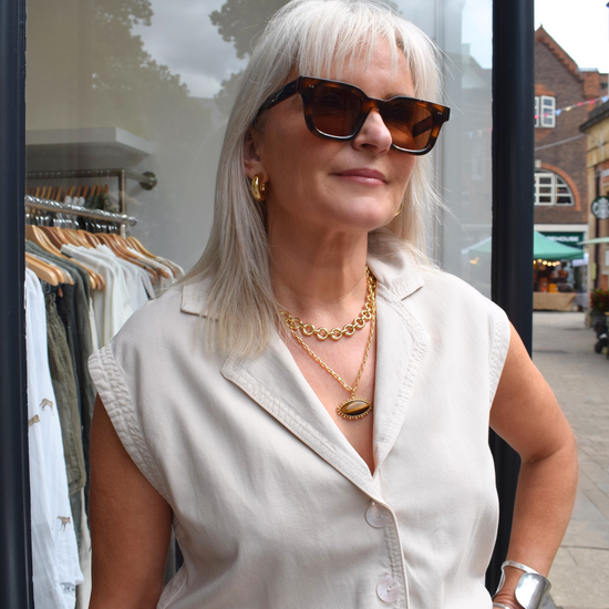 a photo styling up a beige sleevless playsuit with a tie belt 