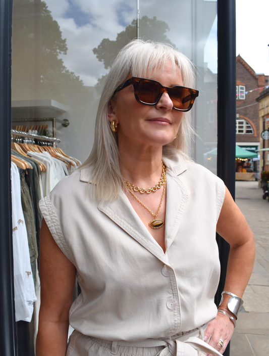 a photo styling up a beige sleevless playsuit with a tie belt 