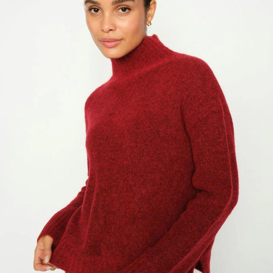 Woman wearing a red turtleneck sweater against a white background