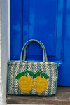 Blue and beige stripe bag with lemons leaning against a blue door