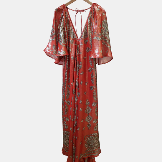 Red and gold patterned dress on a hanger against a white background