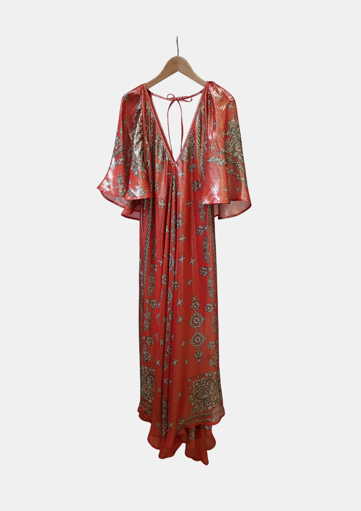 Red and gold patterned dress on a hanger against a white background
