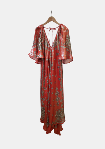 Red and gold patterned dress on a hanger against a white background