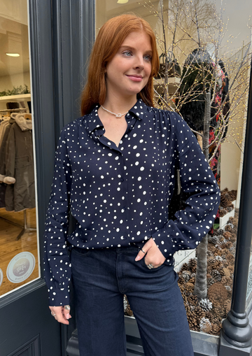 Navy long sleeved shirt with different sized white dots, styled with dark denim.