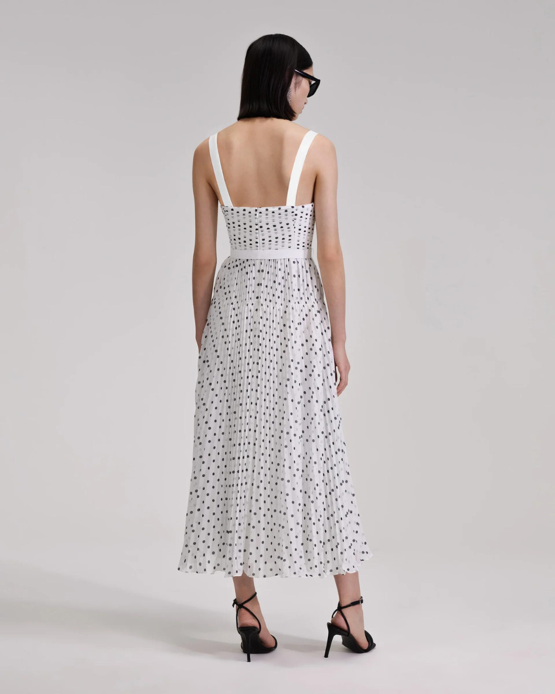 White and black polka dot midi dress with thin straps and fitted bodice with pleating throughout