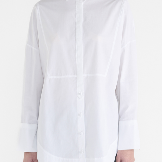 White long classic shirt with wide cuffs and panelling detailing on the front. Close up view