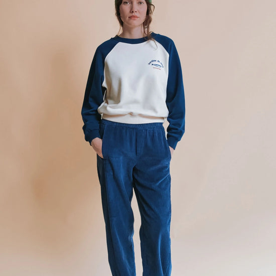 Woman wearing white and blue sweatshirt and blue trousers