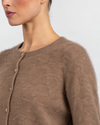 Close-up of a model wearing a fuzzy taupe-brown knit cardigan sweater with a buttoned front.